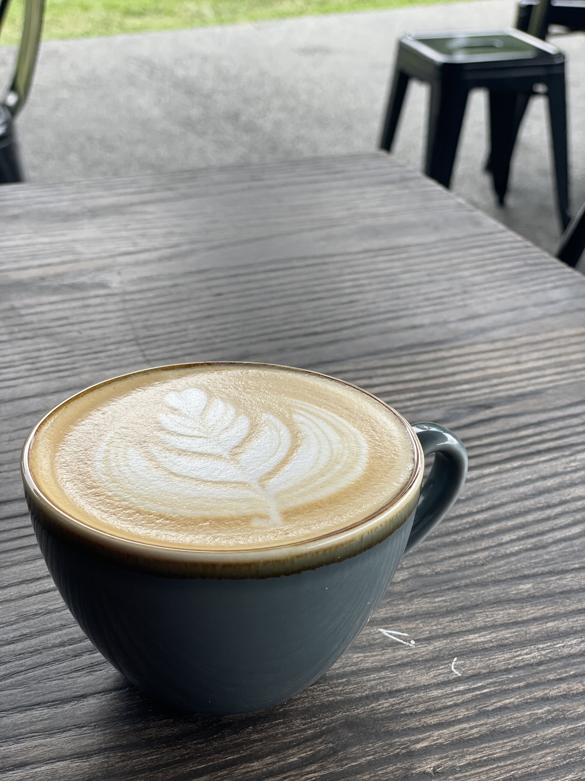 Latte art in a cup on an outdoor wooden table